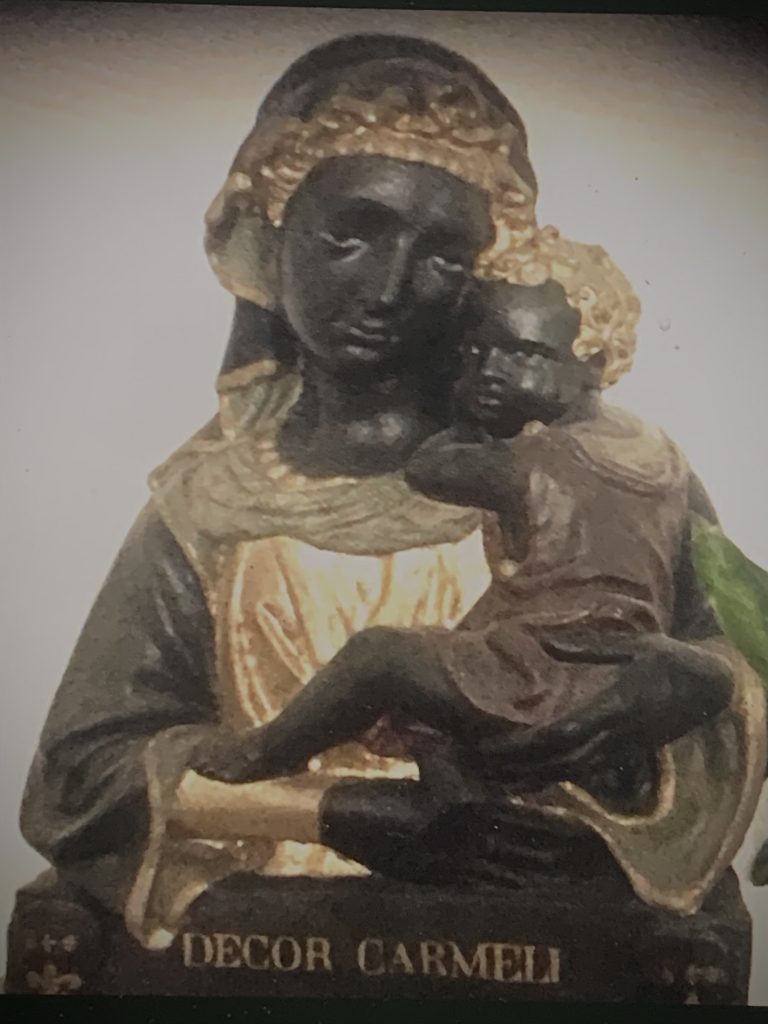 Bottega di Lorenzo Ghiberti, Mezza figura della Madonna col Bambino in braccio su base con stemmi gigliati e iscrizione "DECOR CARMELI/ORA PRO NOBIS", ante 1455, stucco con iscrizione e policromia non originali.
